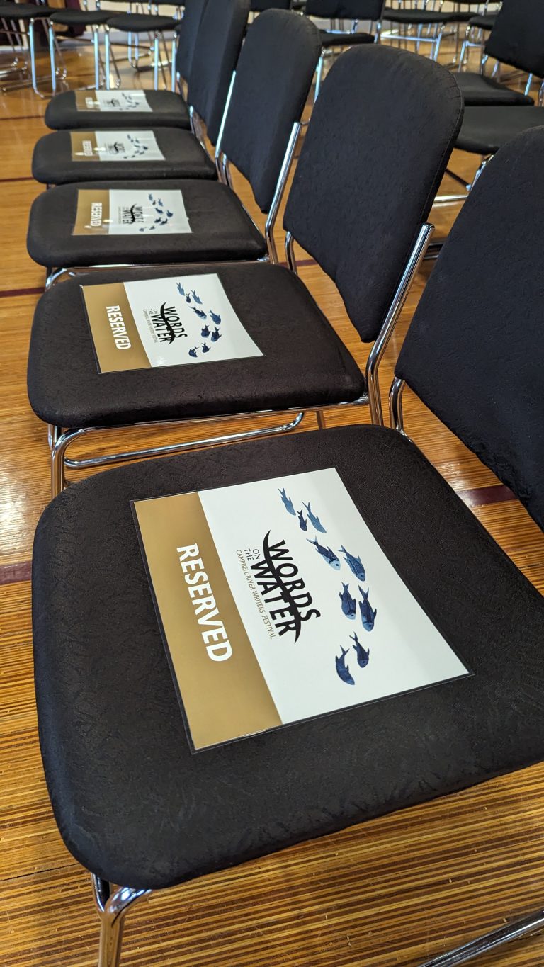 Rows of black chairs with papers labeled "Words Matter" and "Reserved" on the seats, set up on a gymnasium floor.